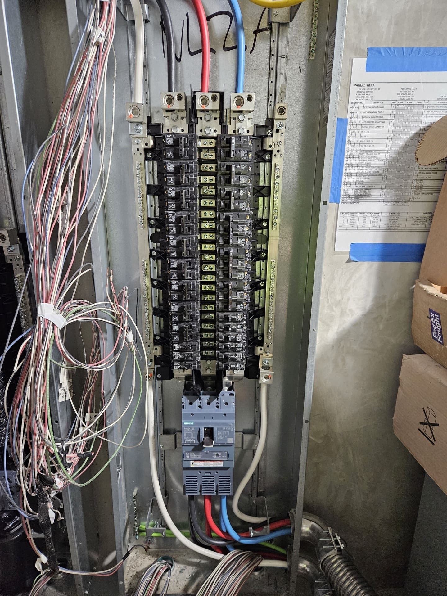 A 400 amp panelboard loaded out, with the panel schedule and its load calculation taped up alongside