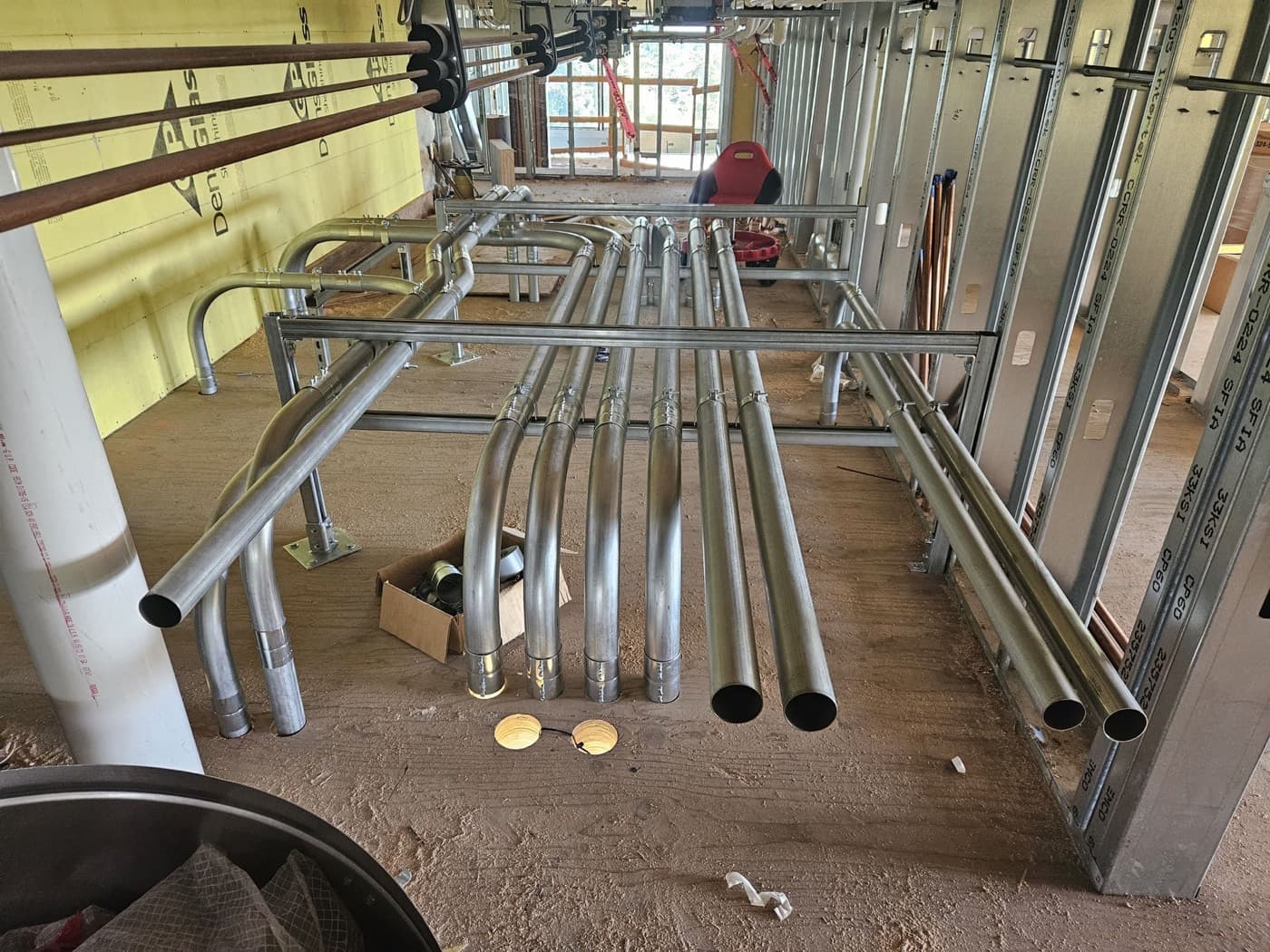 Small commercial electrical rough in with parallel conduit runs racked through steel stud framing