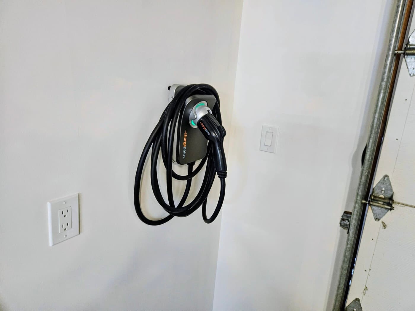 EV charger installation on a garage wall beside the door with the cable coiled clear of the floor