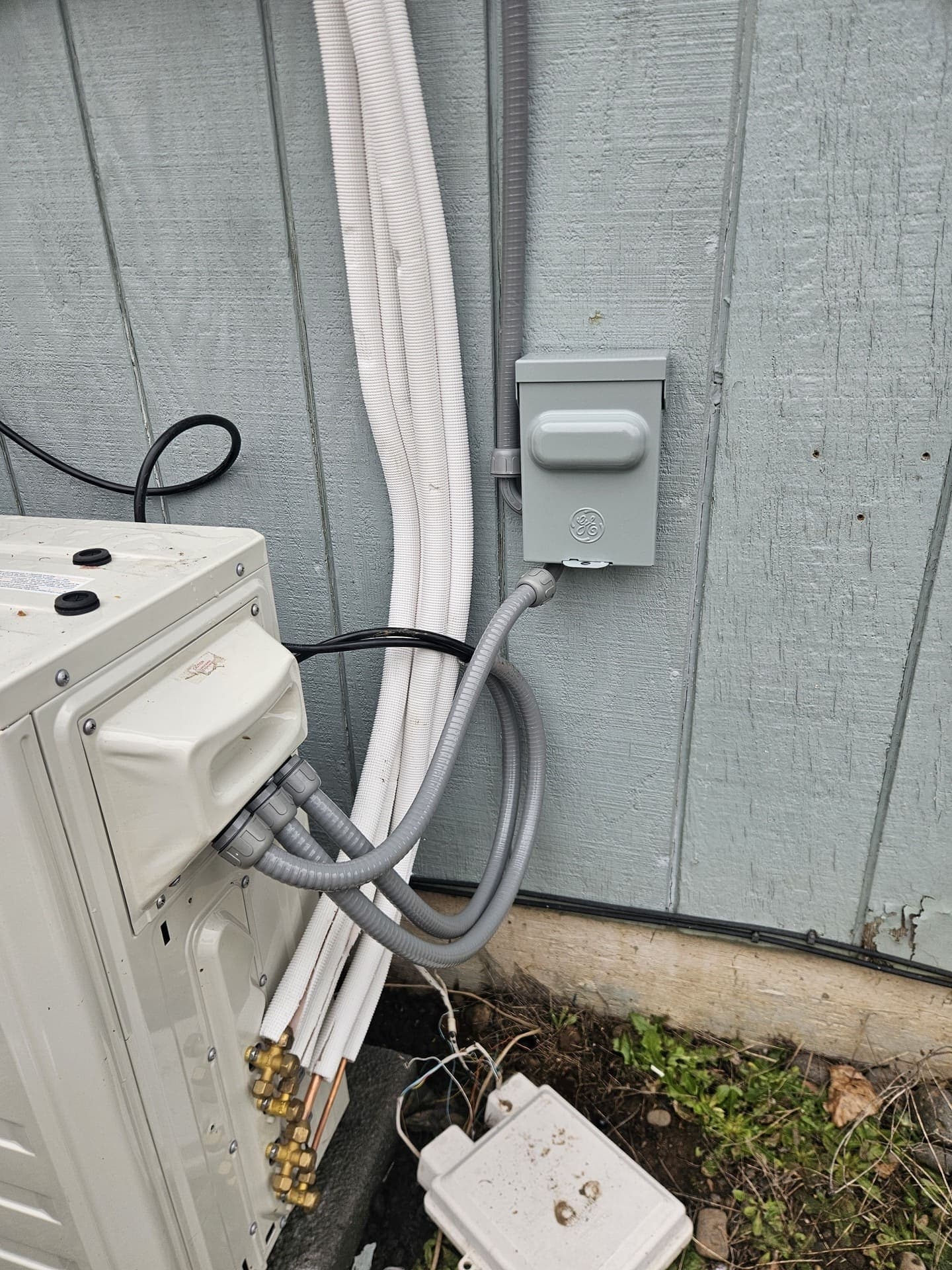 A weatherproof disconnect on a wall with flexible conduit whips dropping into a mini split unit
