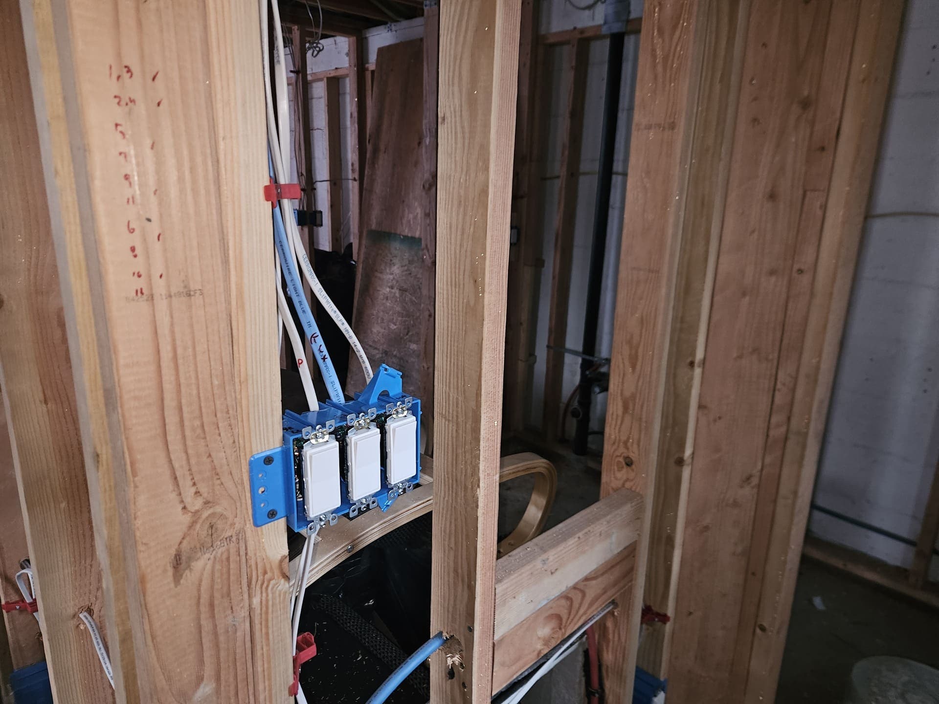 A three-gang switch box set in open framing with its cables run and stapled during rough-in