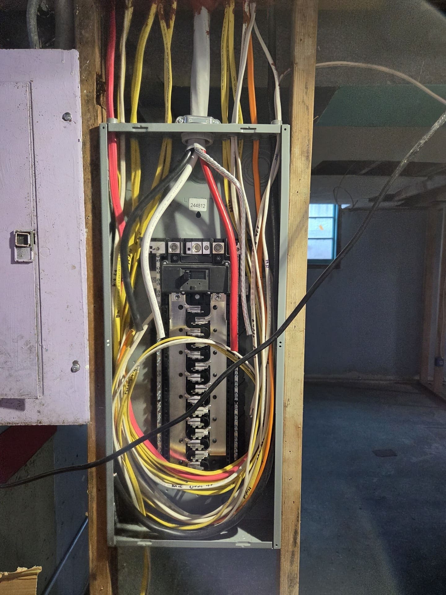 A new service panel mounted on a basement beam with its feeders and branch circuits dressed in