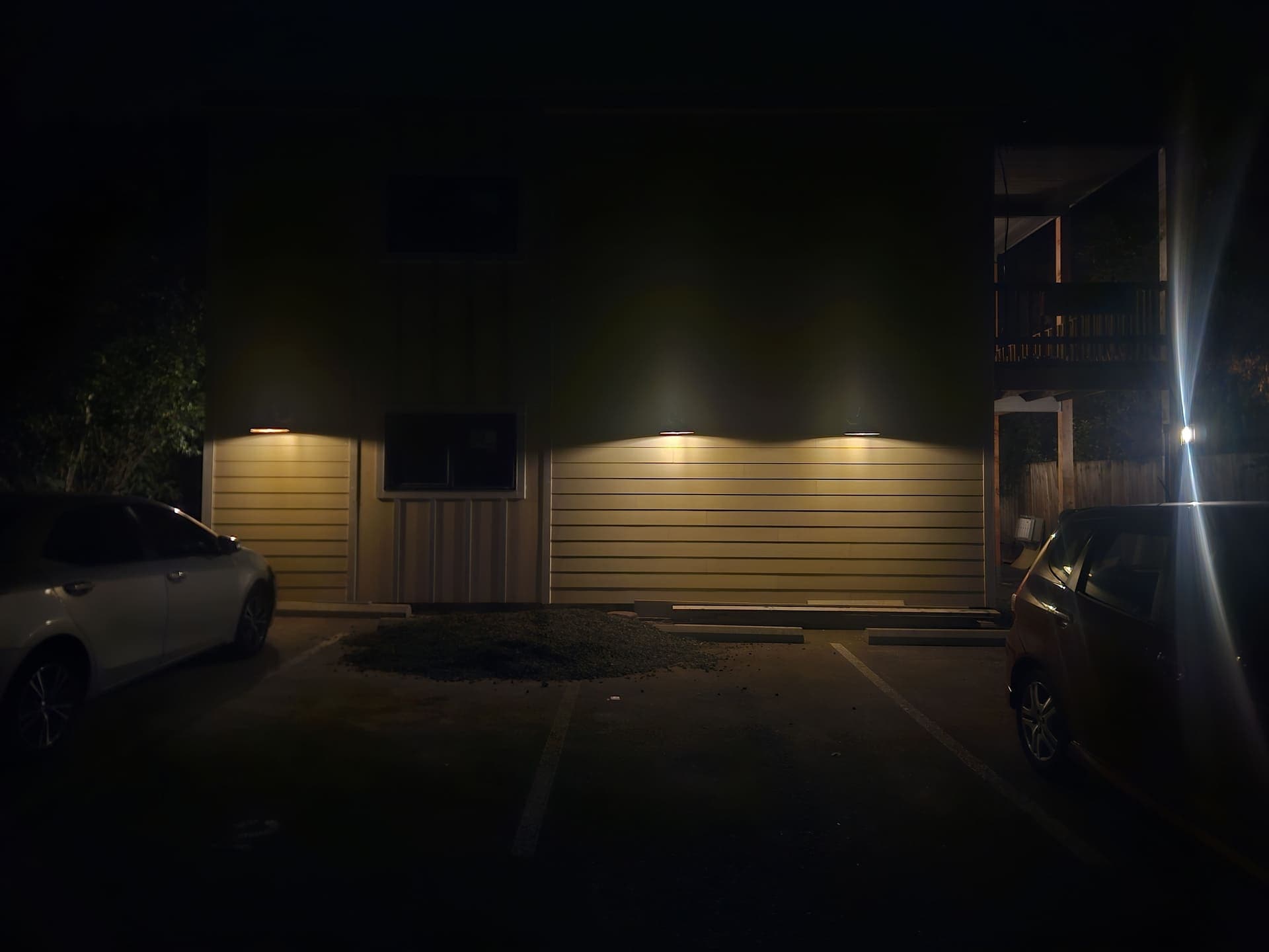 Exterior wall packs lighting the parking area and entries of a four-plex after dark