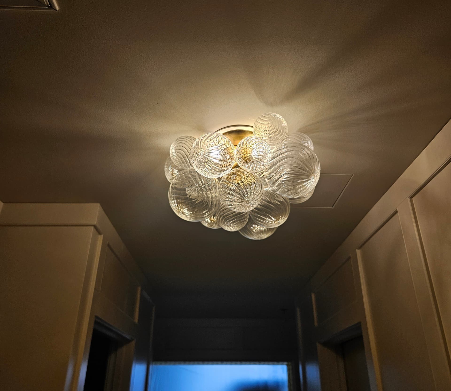 A cluster of ribbed glass globes on a brass flush mount lighting a hallway