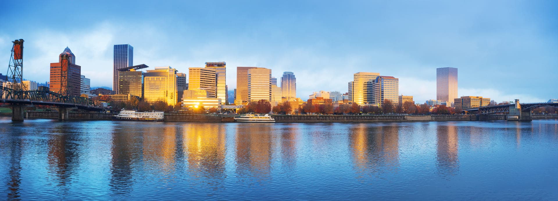 Downtown Portland, Oregon at dusk seen across the Willamette River, with the Hawthorne Bridge to the left