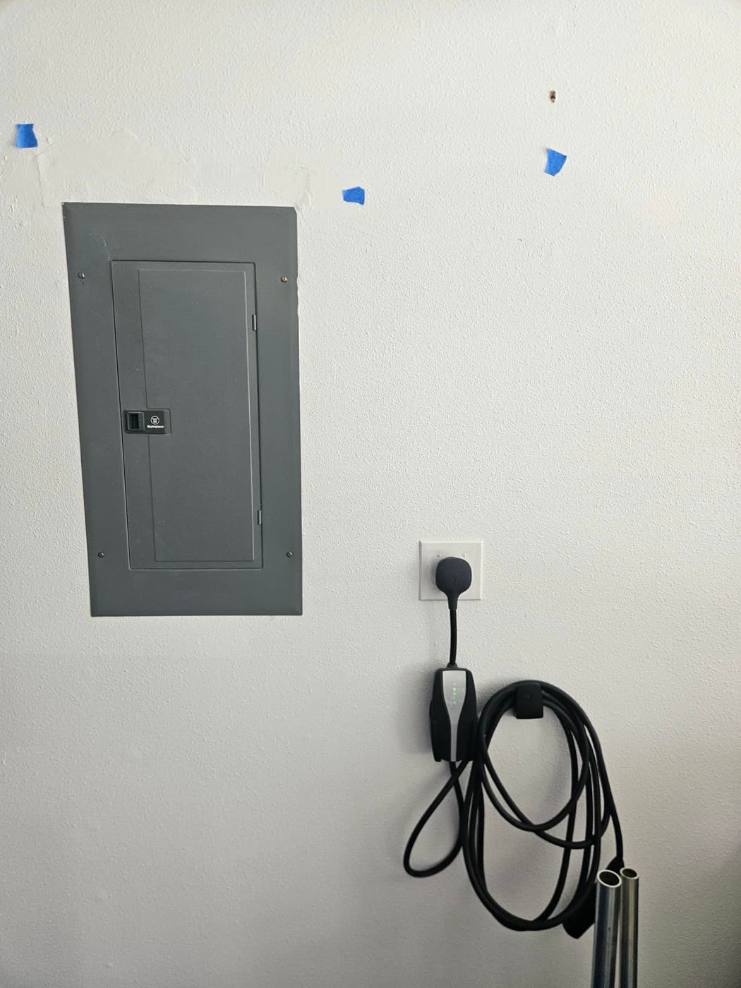 EV charger fed from a dedicated breaker in the electrical panel mounted beside it