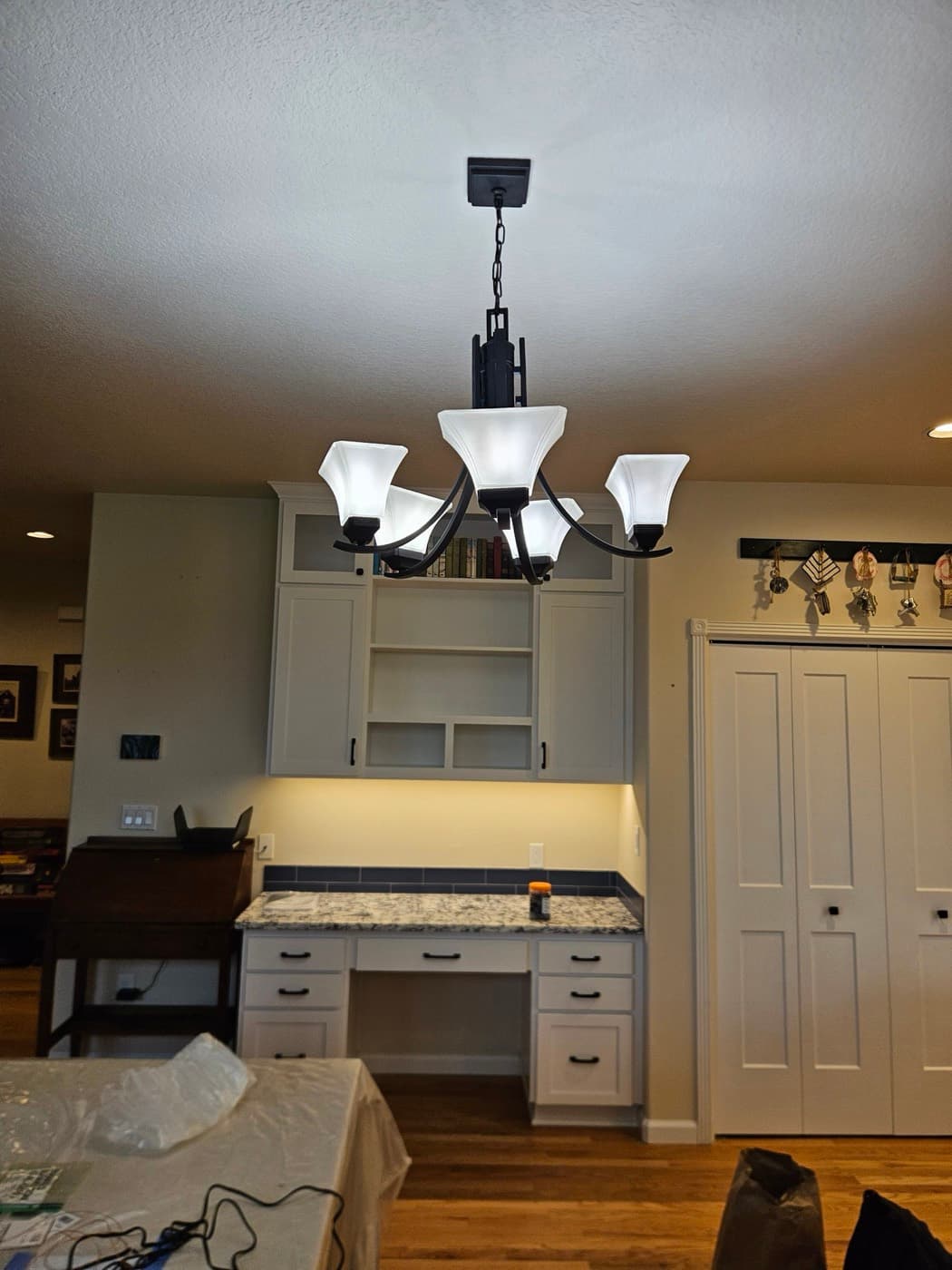 Five arm chandelier over an entry with under cabinet lighting on the counter behind