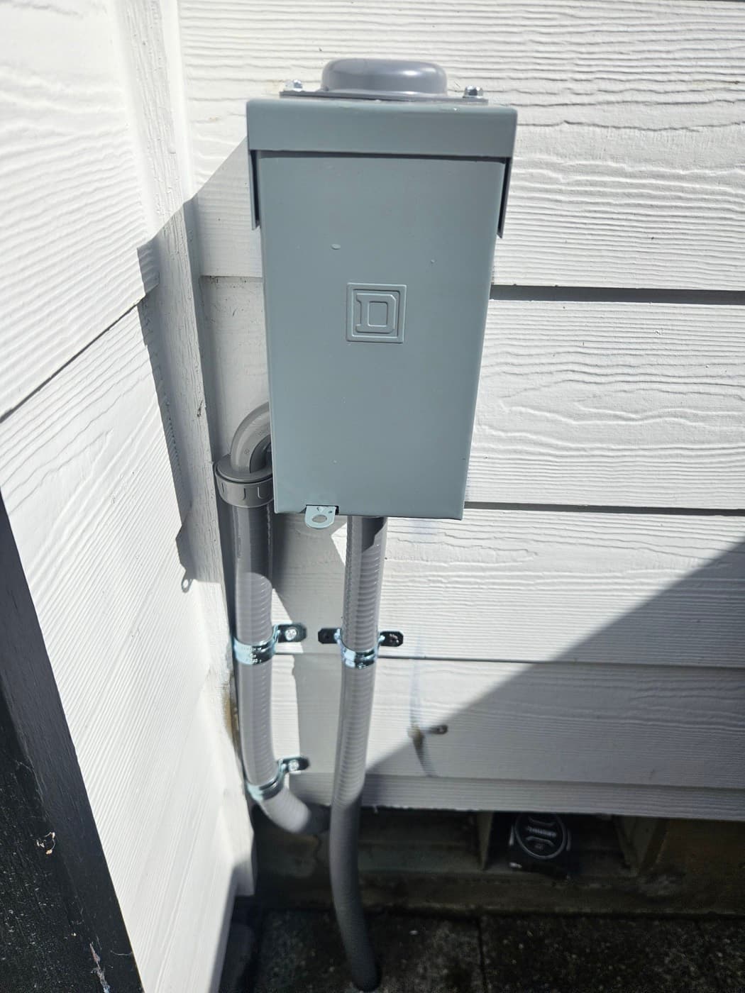 Weatherproof spa disconnect box mounted on an exterior wall for a hot tub circuit