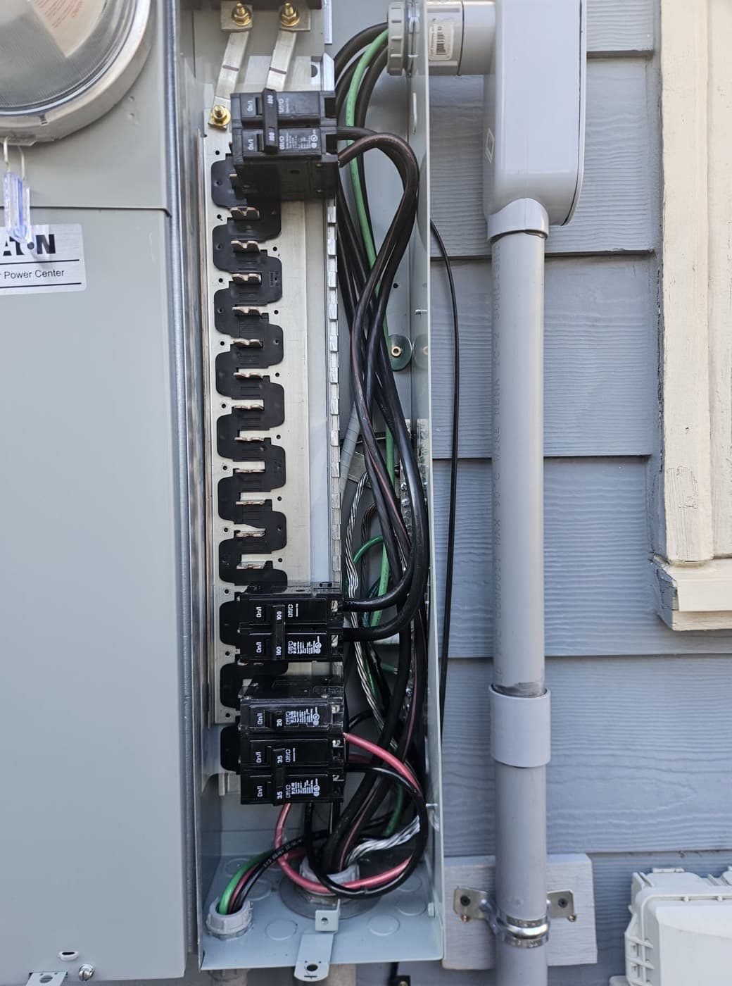 Exterior electrical enclosure opened up with breakers landed and flexible conduit entering below