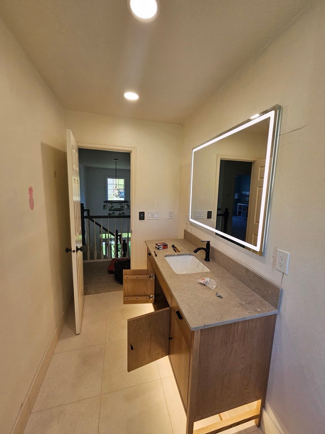 Backlit vanity mirror wired into a finished bathroom remodel