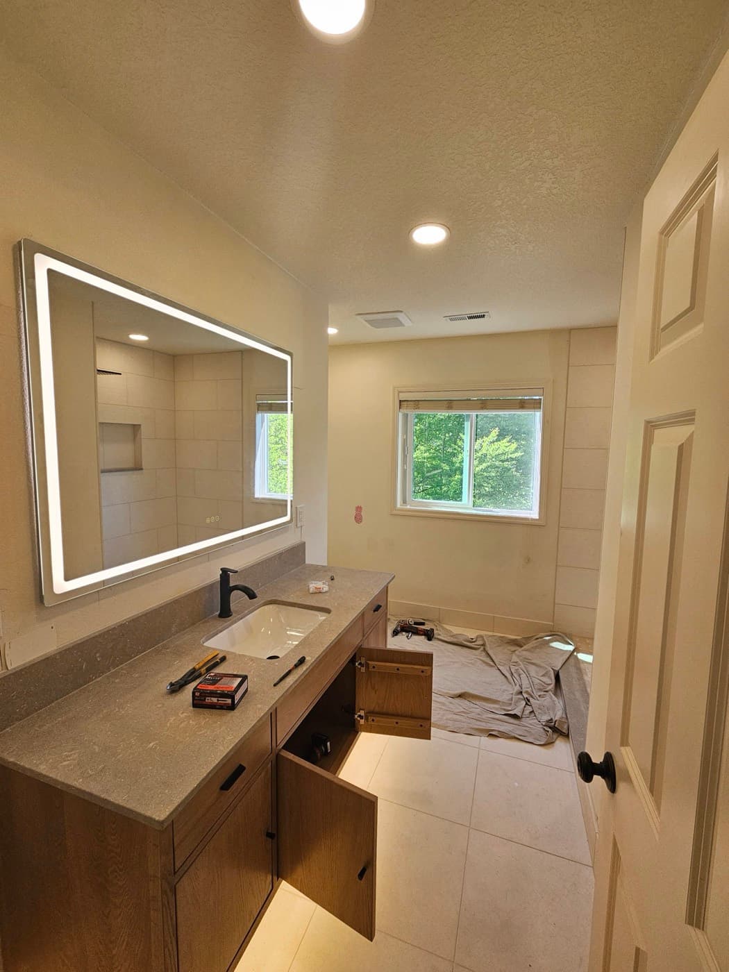 Finished bathroom vanity run with a backlit mirror and recessed ceiling lights