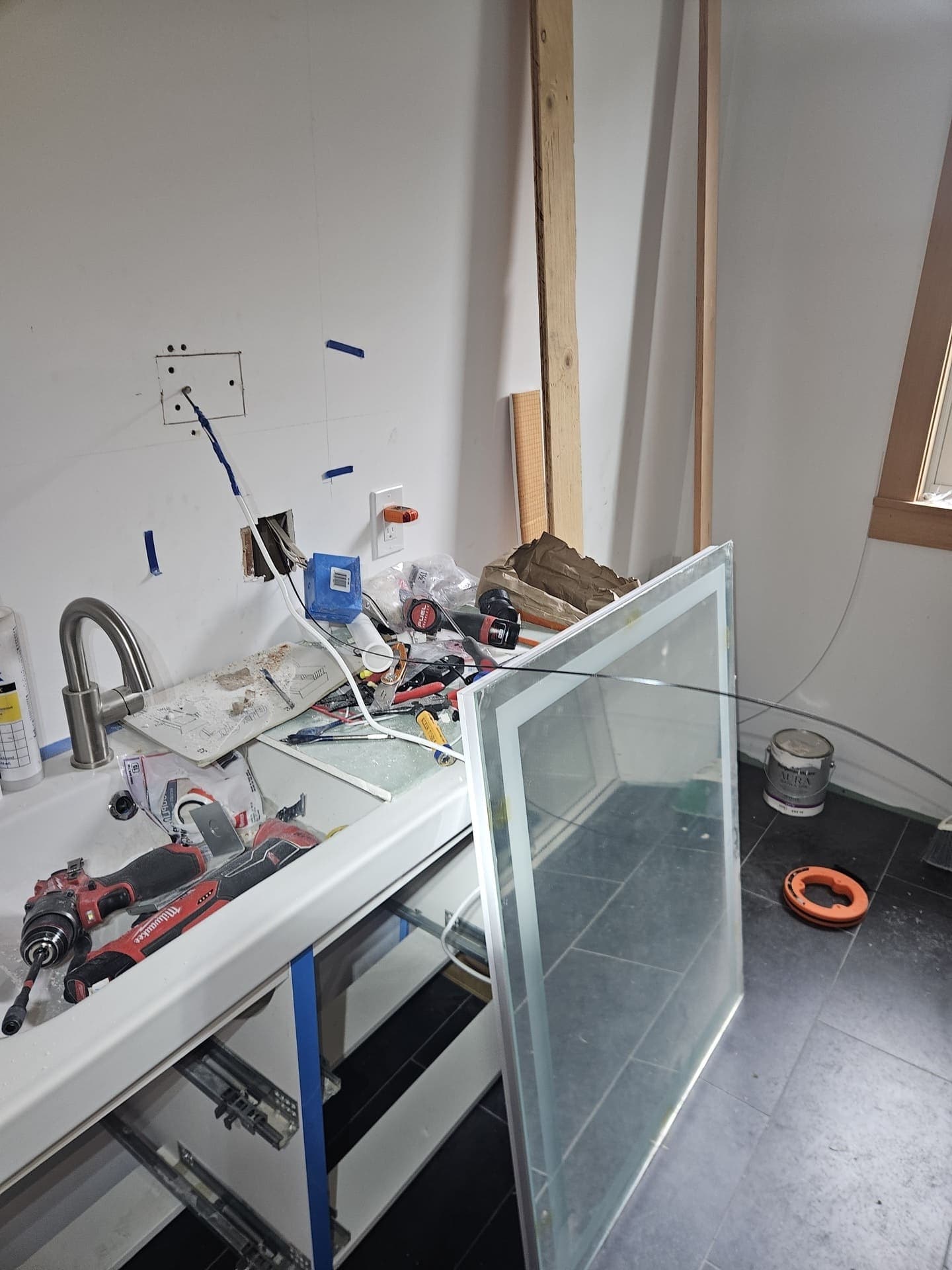 An LED mirror being wired in at a vanity, with the feed run to the box before the glass goes up