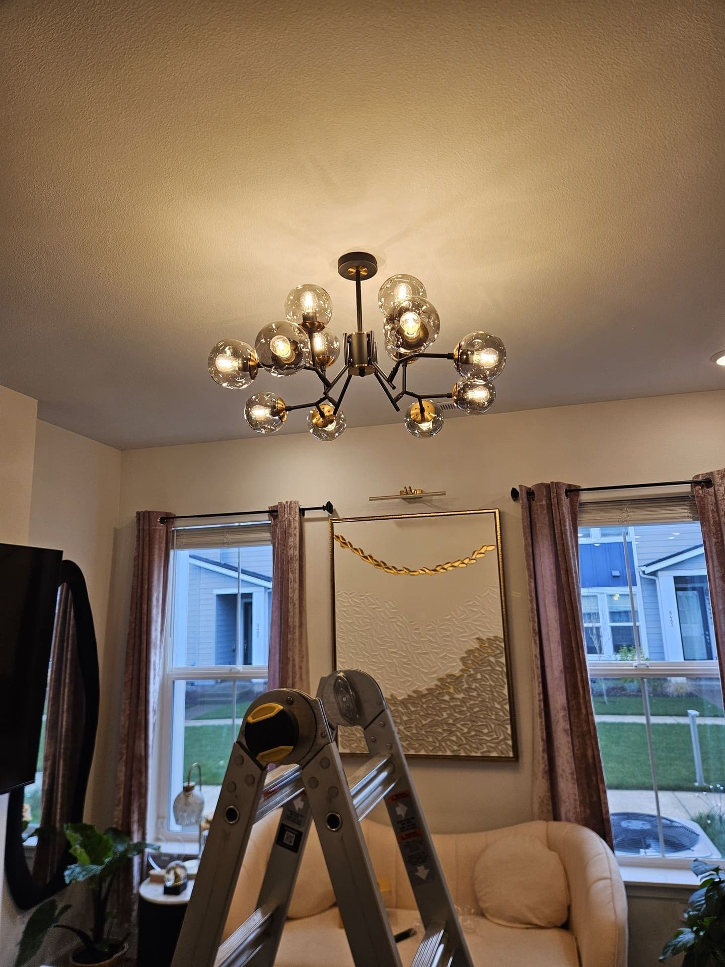 A multi globe chandelier hung and lit over a living room, fed from a new ceiling box