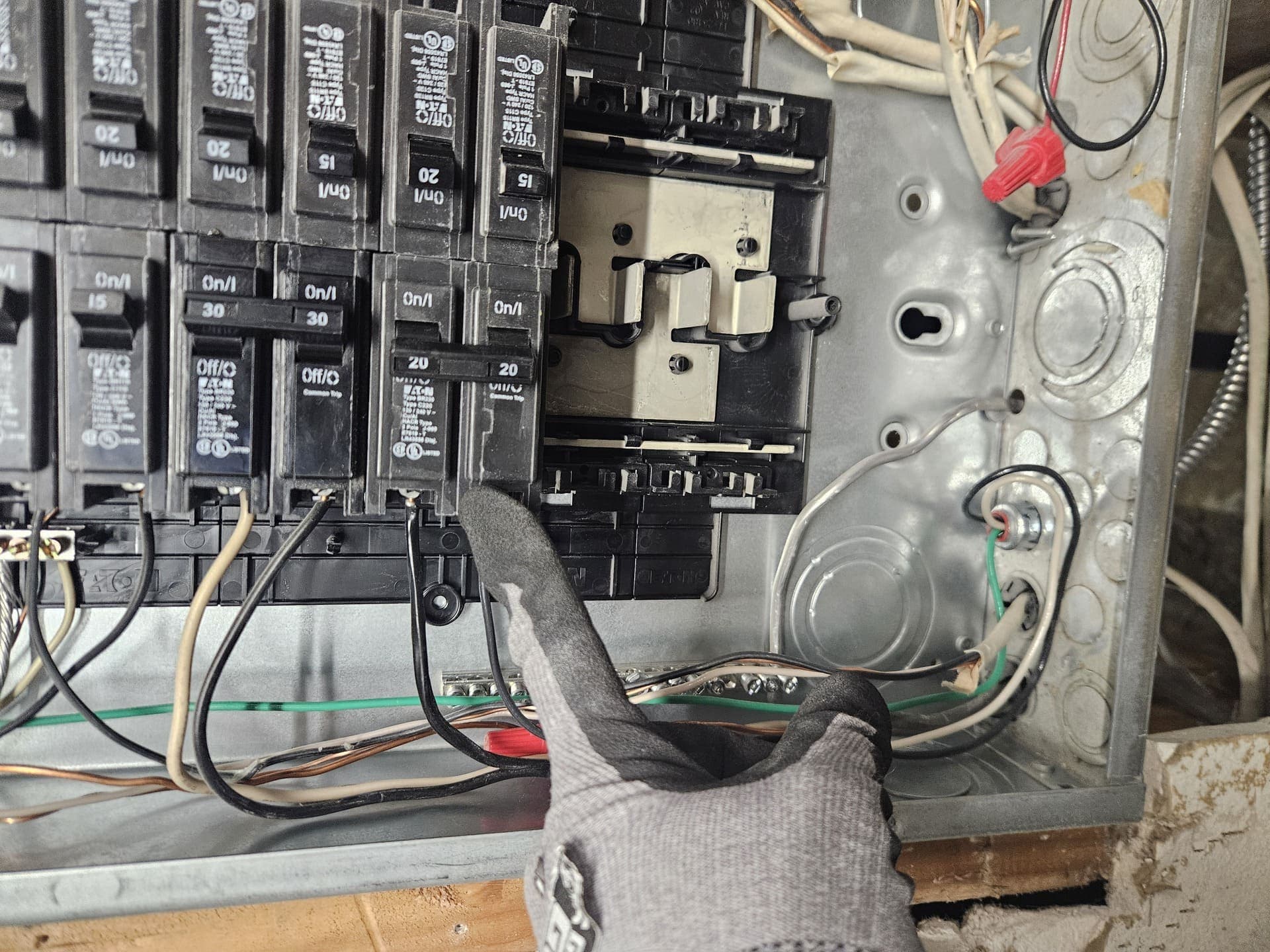 An open panel with the dead front off and a gloved hand at the breakers during troubleshooting