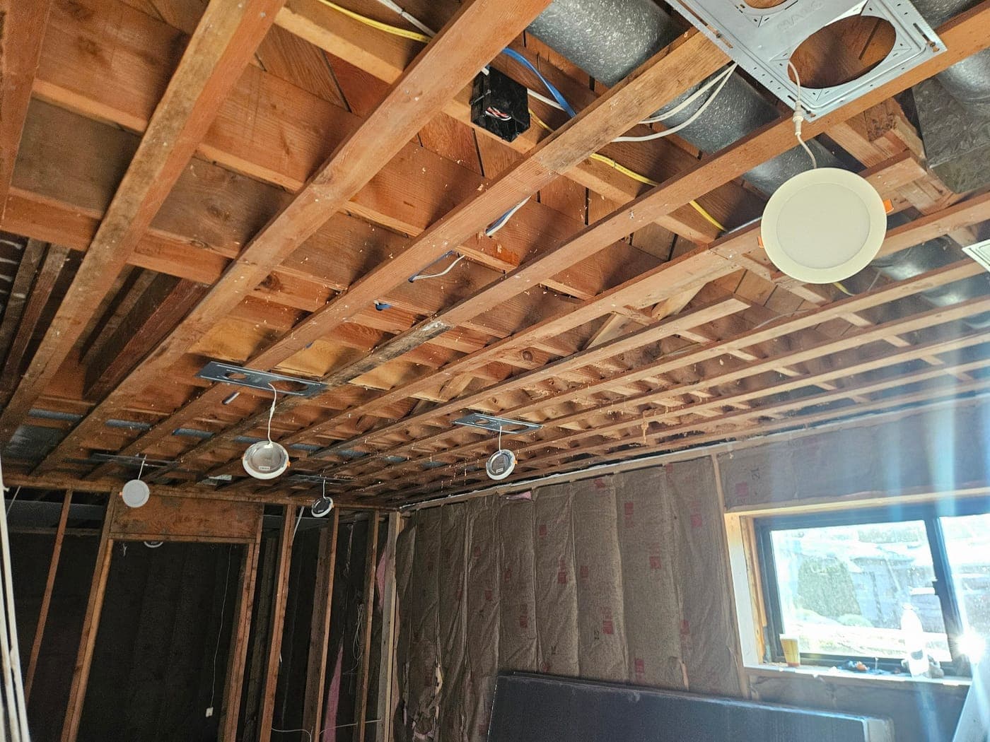 Recessed can housings hung between the floor joists of a basement during rough in