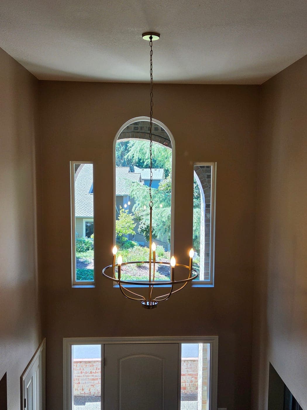 A second brass orb chandelier in the same house, hung in the entry above an arched window