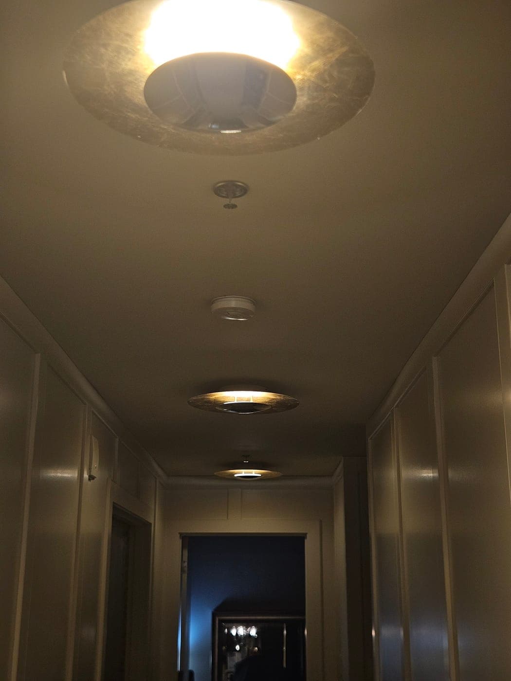 Four flush mount ceiling lights lighting a panelled hallway at night