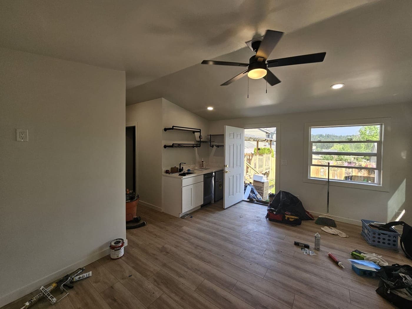 A newly built room with a ceiling fan and recessed cans in, before the walls were finished