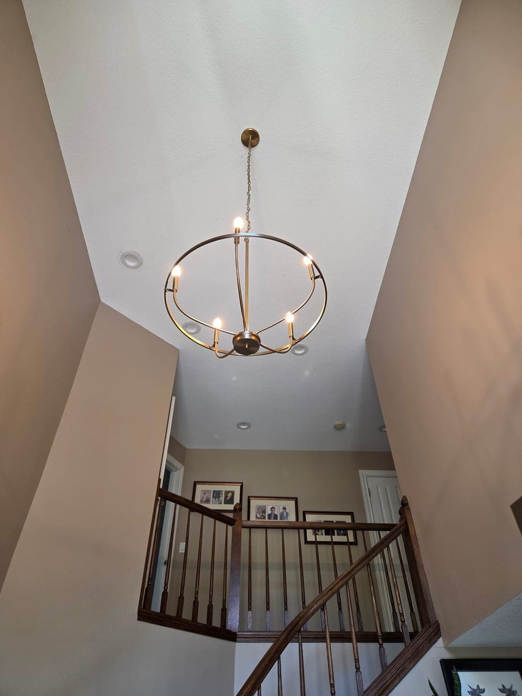 A brass orb chandelier hung in a two storey stairwell above the landing