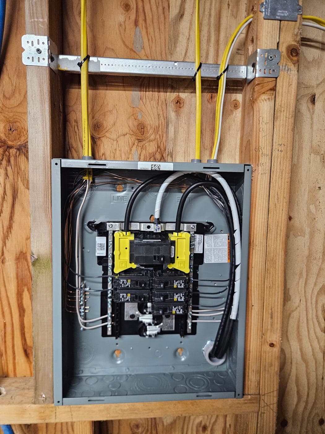 A subpanel mounted on plywood sheathing with its feeders looped in and every circuit landed