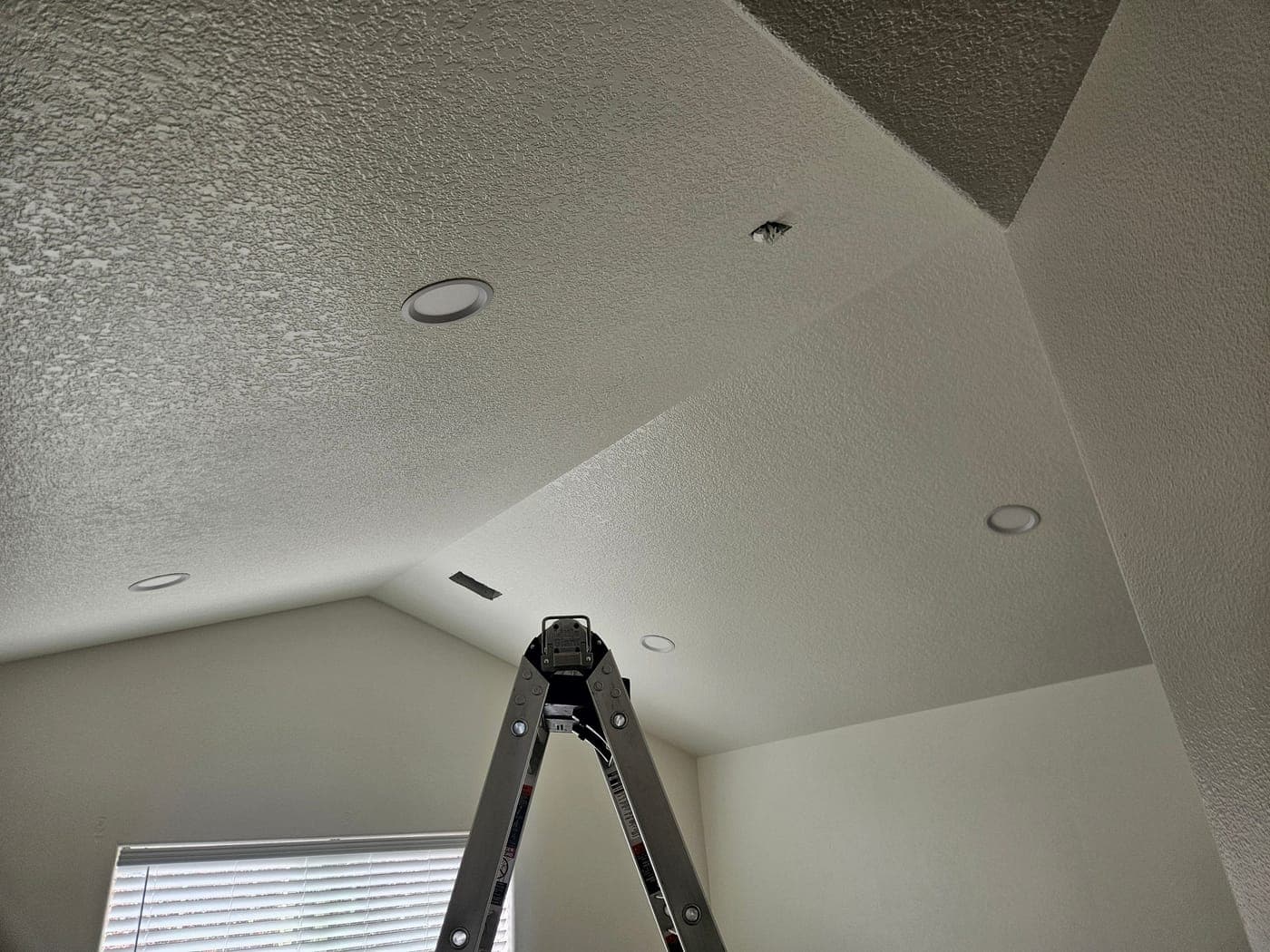 Recessed cans set into a vaulted ceiling with the ladder still standing under them